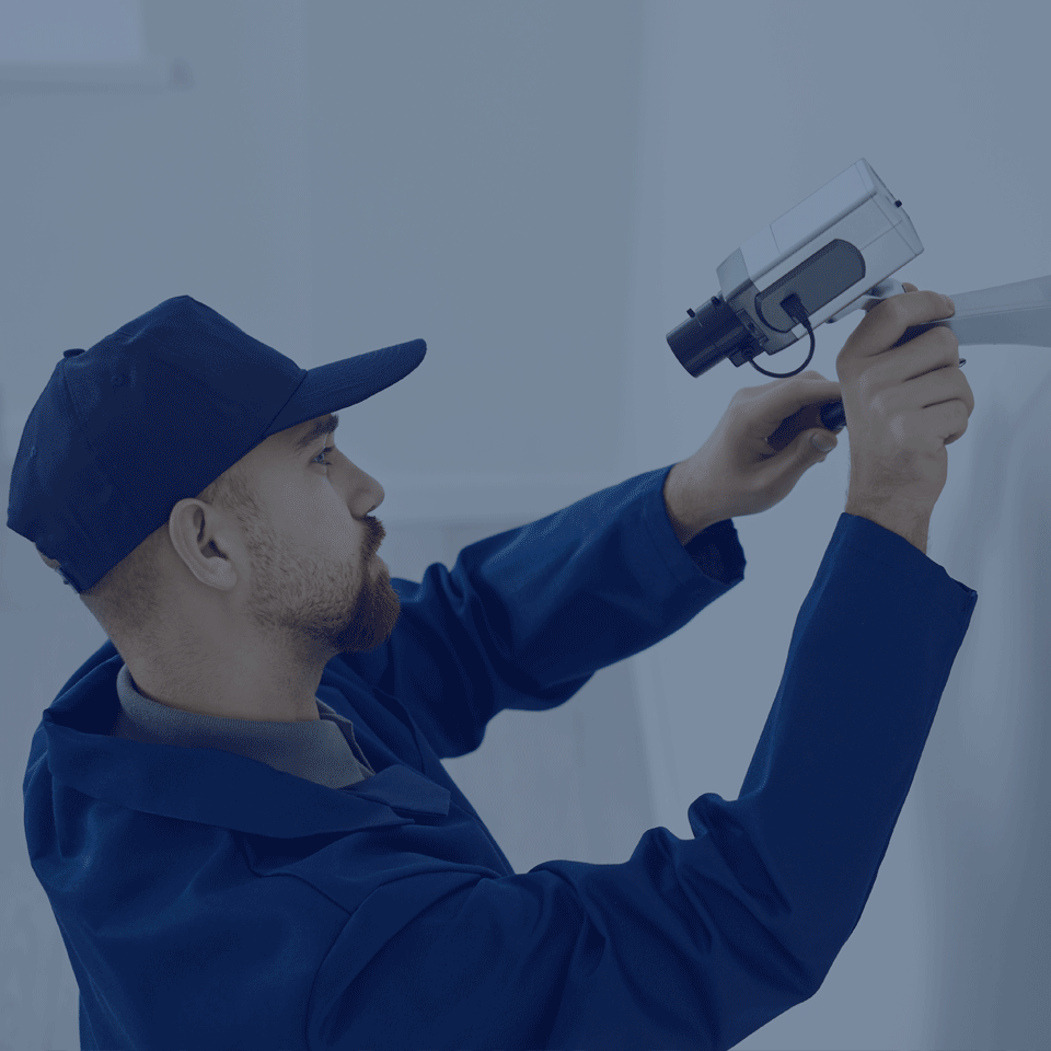 Installing Side Camera Man Installing a Security Camera on the side of a building